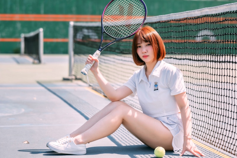 Asian woman with tennis racket on court