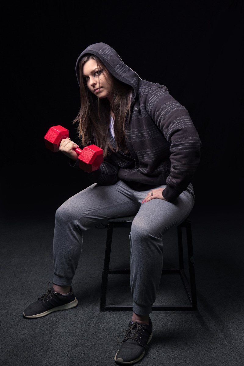 Corinne sitting and lifting a dumbbell