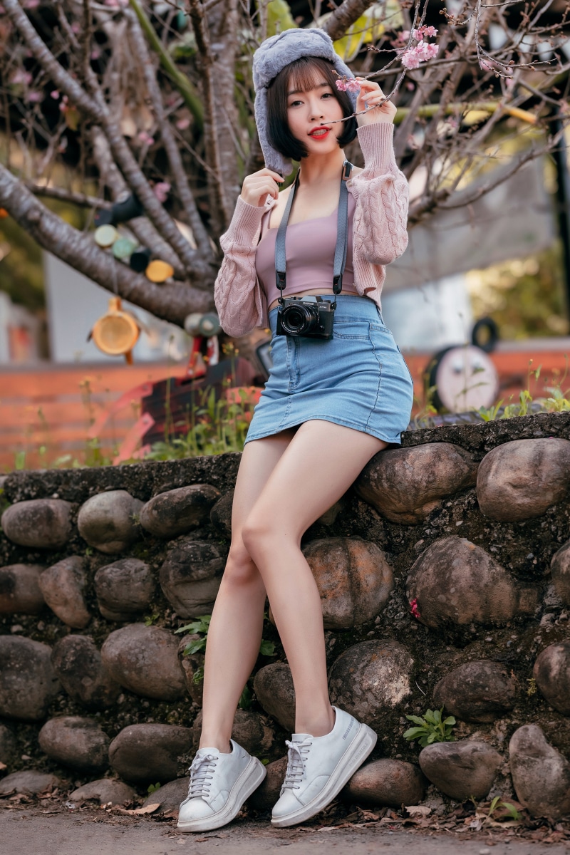 Asian woman in winter hat and denim skirt with camera