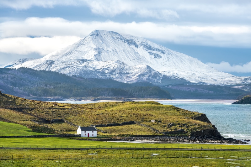 White house on a hill with snow-capped mountains