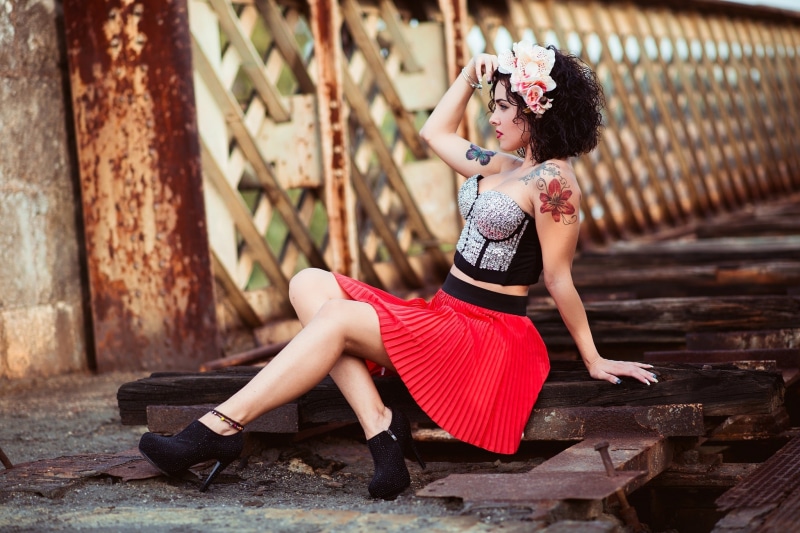 Brunette girl with tattoos sitting on wooden planks