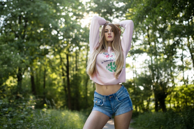 Blonde girl in sweater and shorts in forest