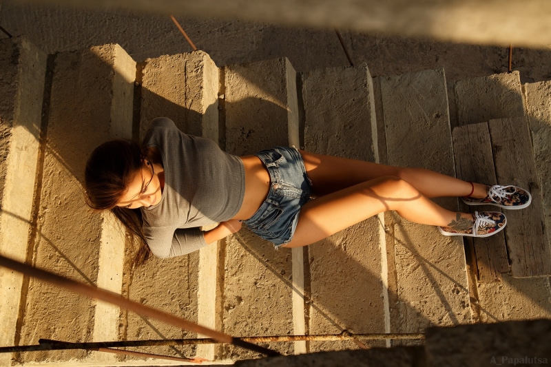 Brunette girl in shorts lying on stairs