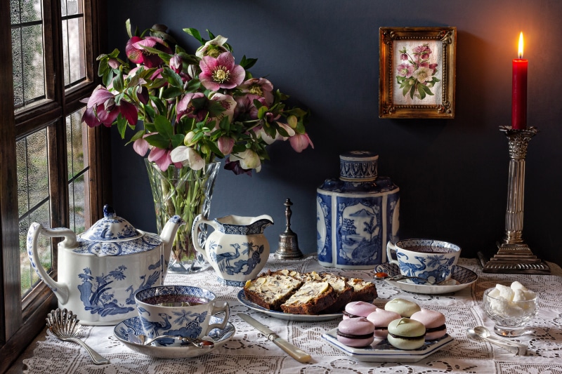 Still-life with tea set, flowers, cake, and macarons