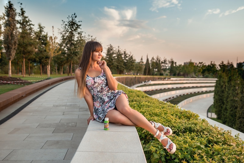 Woman in floral dress sitting on a ledge in a park