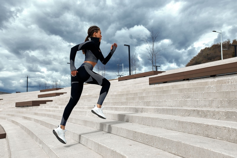 Woman running up concrete stairs in athletic wear
