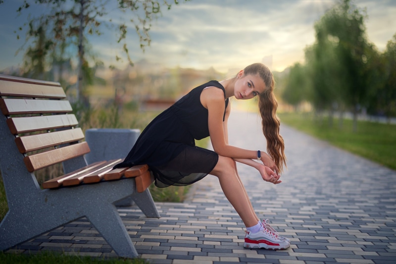 Woman in black dress sitting on a park bench