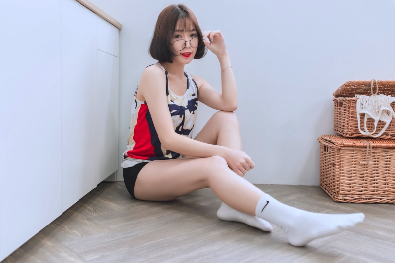 Asian woman sitting on floor wearing singlet and socks