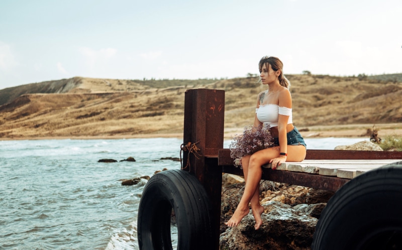 Woman in shorts sitting on a dock with flowers
