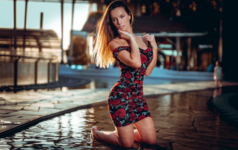 Woman in floral dress kneeling by water