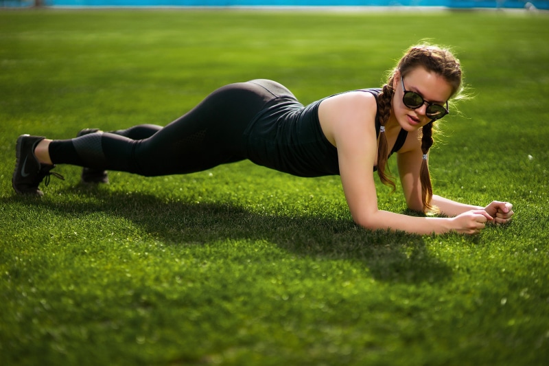 Woman doing plank exercise on grass