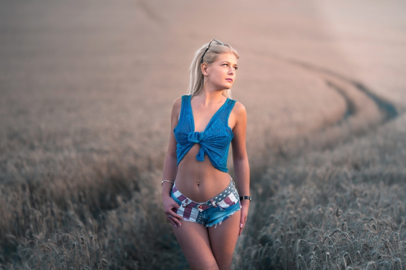 Blonde girl in shorts and blue top in a field
