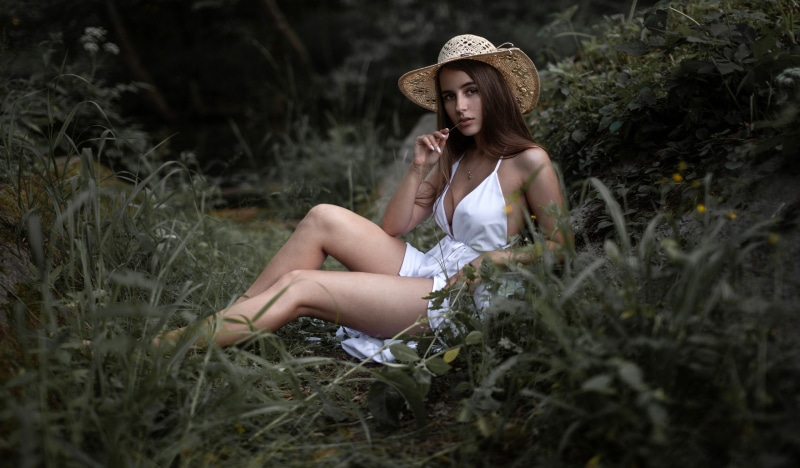Nadezhda Zvezdochkina wearing a straw hat and white dress in grass