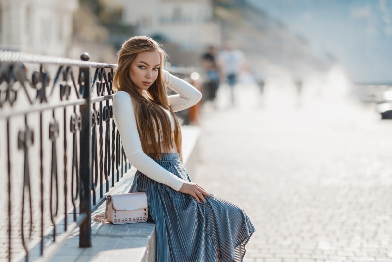 Nika Gekalyuk sitting by a fence with a handbag