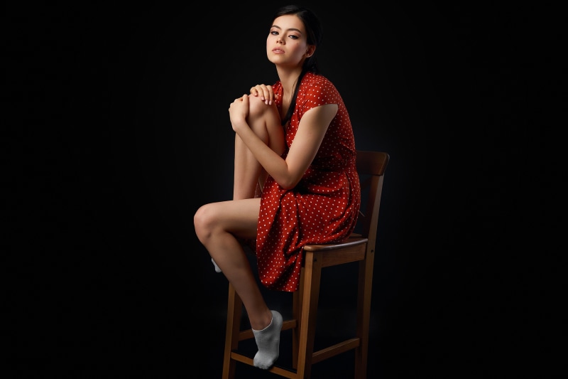 Brunette girl in red polka dot dress sitting on chair