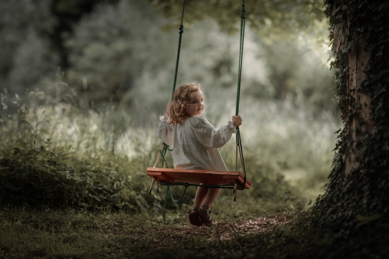 Little girl on a swing in a forest