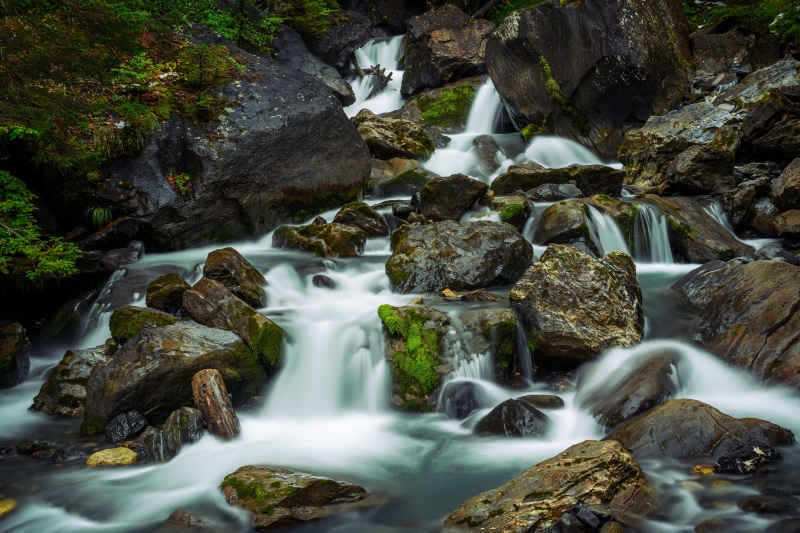 Stream flowing over mossy stones in Gryon, Switzerland