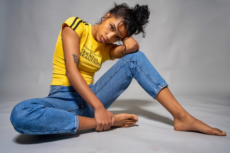 Woman in yellow t-shirt and jeans posing