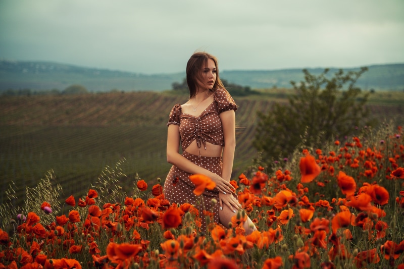 Woman in polka dot dress in a field of poppies