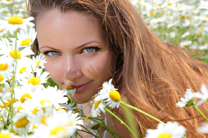 Brown-haired woman in a field of daisies