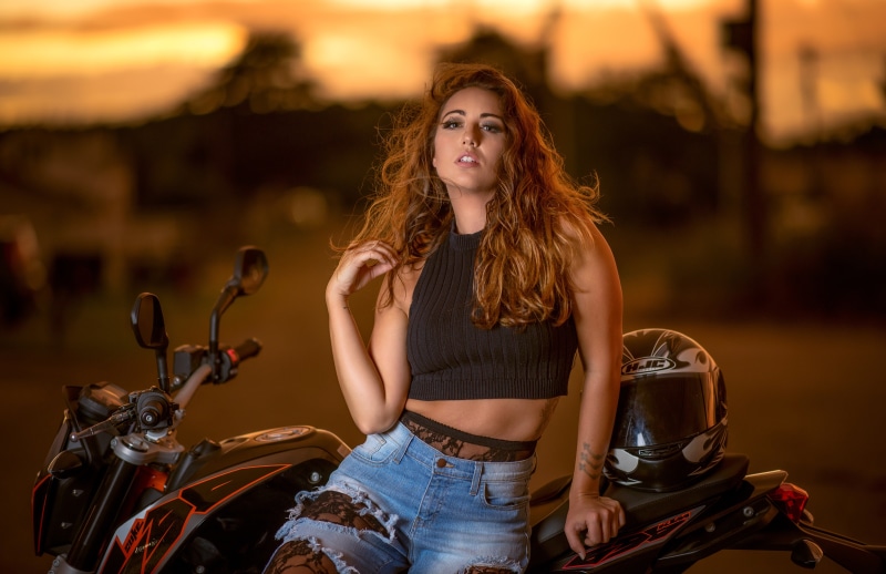 Woman with brown hair on a motorcycle with helmet