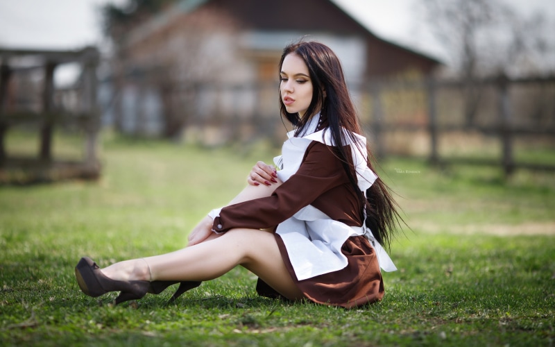 Woman in maid uniform sitting on grass