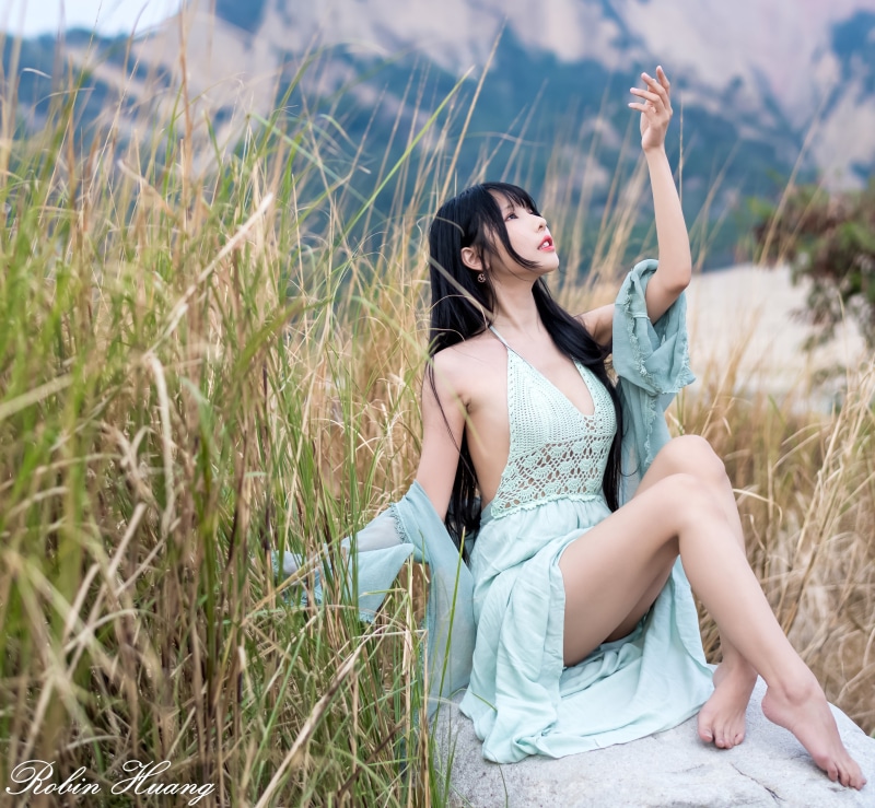 Brunette girl in a dress sitting in grass