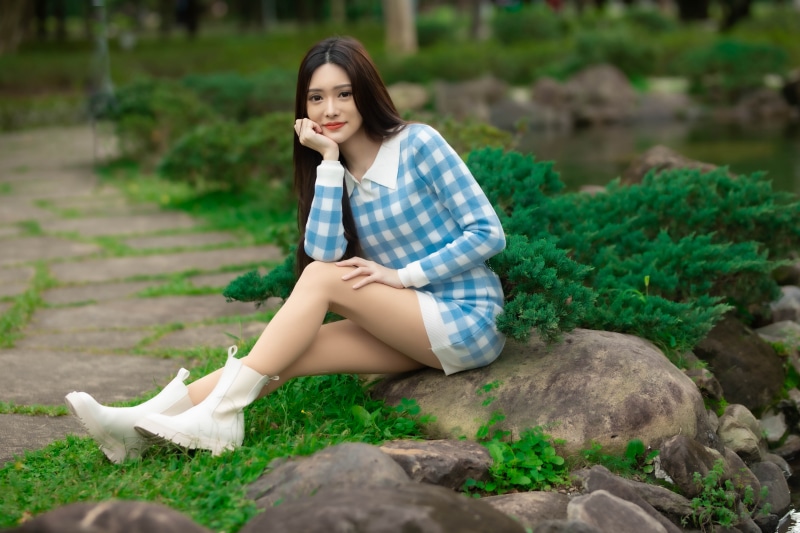 Asian woman sitting on rocks by a pond