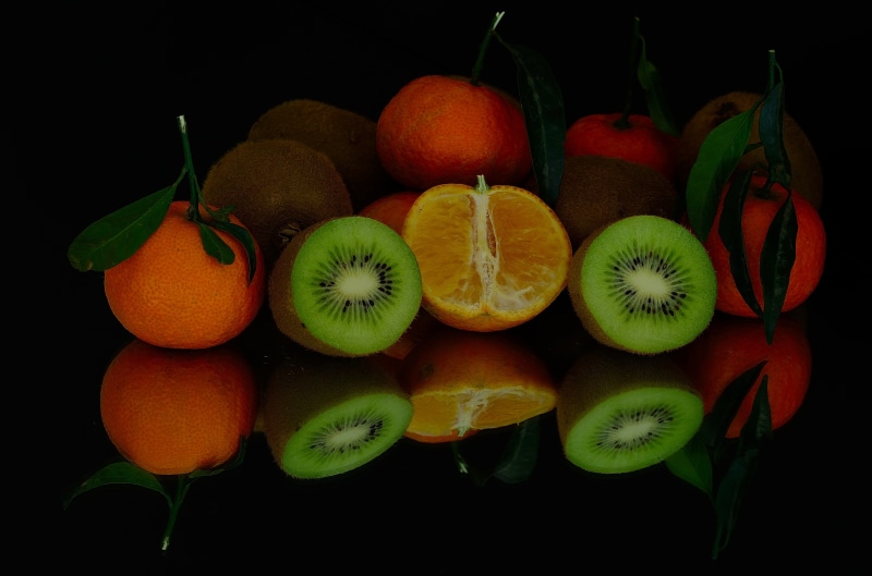 Still life of tangerines and kiwis with reflections