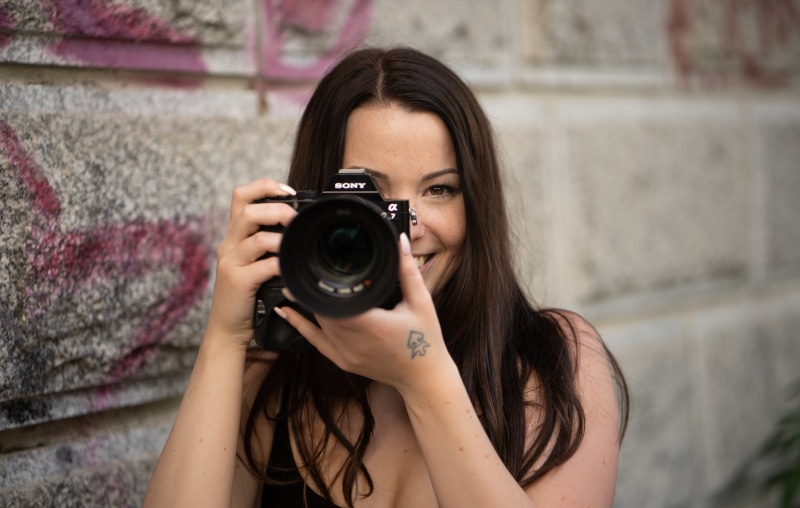 Brunette woman holding a Sony Alpha 7 camera