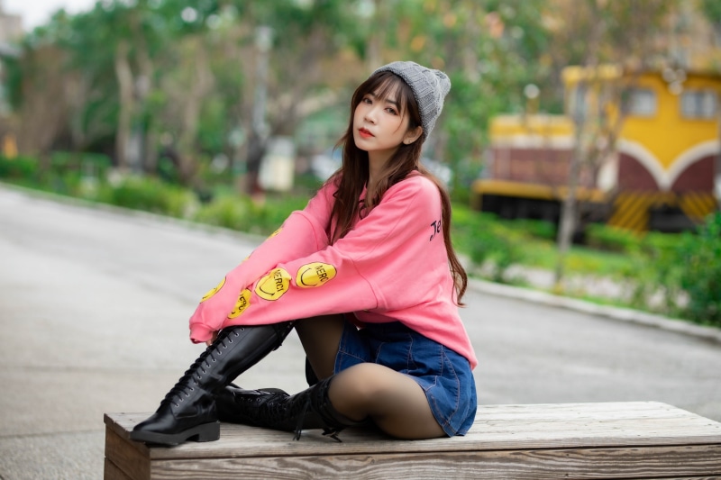 Asian girl wearing winter hat and boots sitting