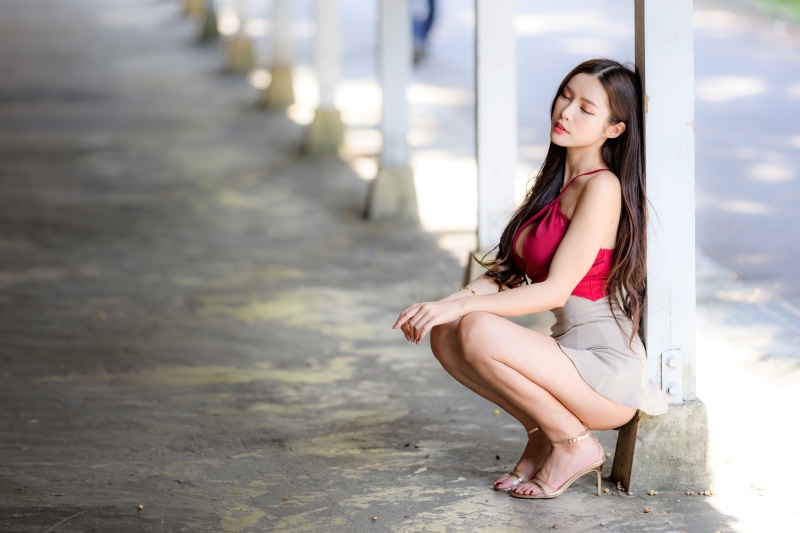Asian woman in red top and skirt crouching