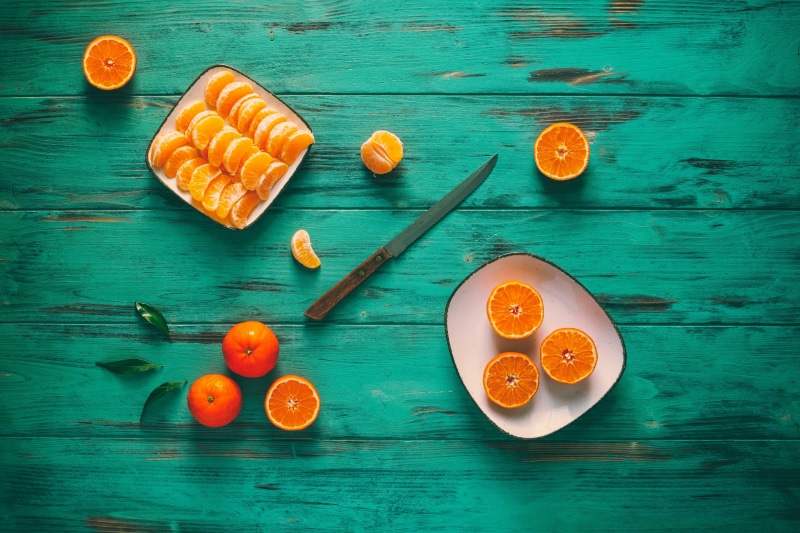 Mandarine slices on a plate with a knife on wood planks