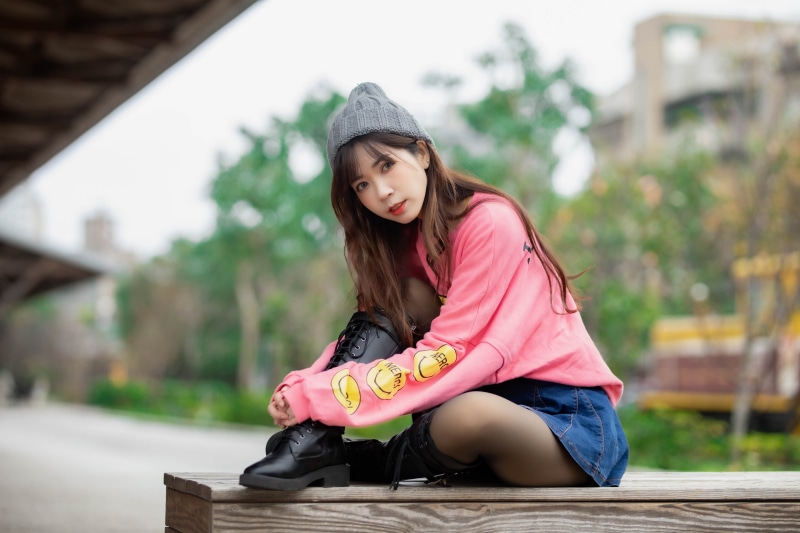 Asian girl in winter hat sitting outdoors