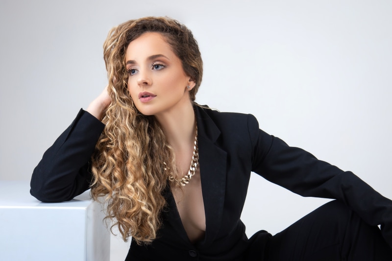 Woman with curly hair wearing a black suit and necklace