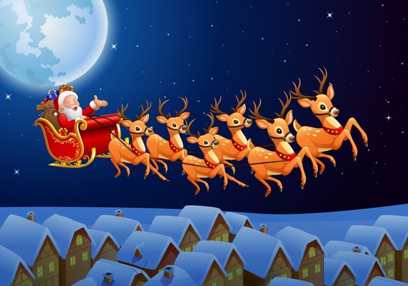 Santa Claus flying in a sleigh with reindeer over snowy houses