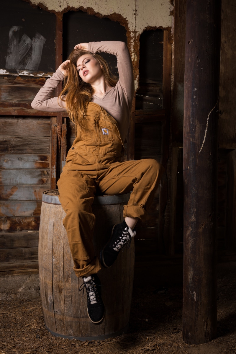 Woman in overalls posing on a barrel