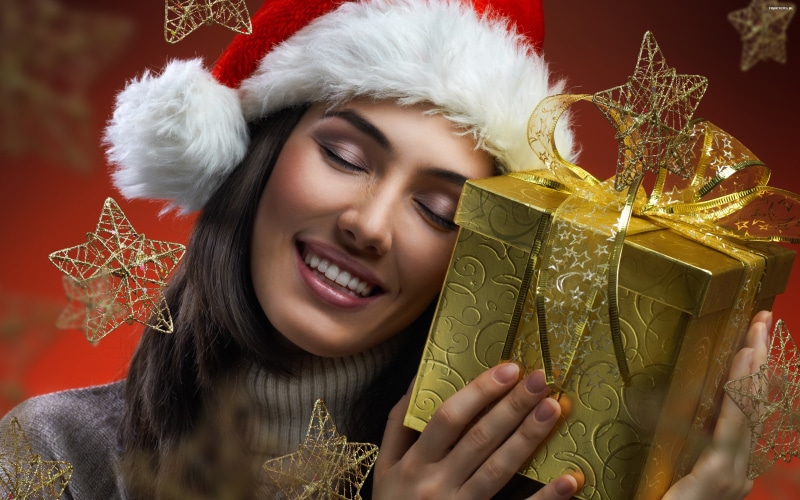Brunette girl in Santa hat with Christmas gift