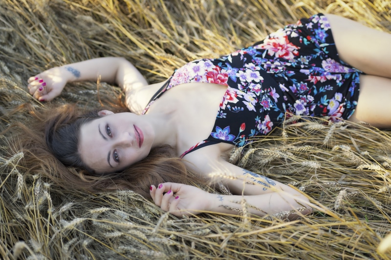 Woman in floral dress lying in a wheat field
