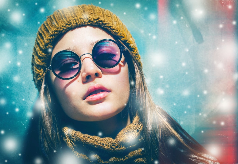 Girl in winter hat and sunglasses with snow