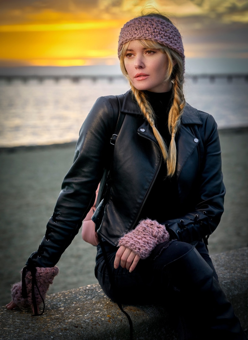 Woman with blonde braids and leather jacket at sunset