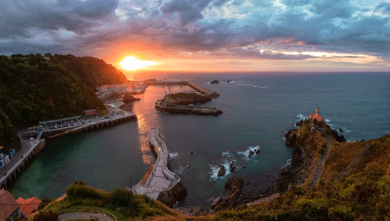 Sunset over a coastal town with a lighthouse
