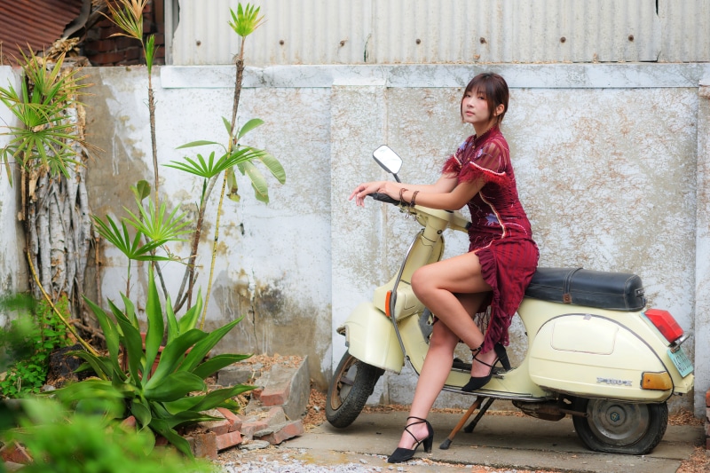 Asian woman in red dress on a scooter