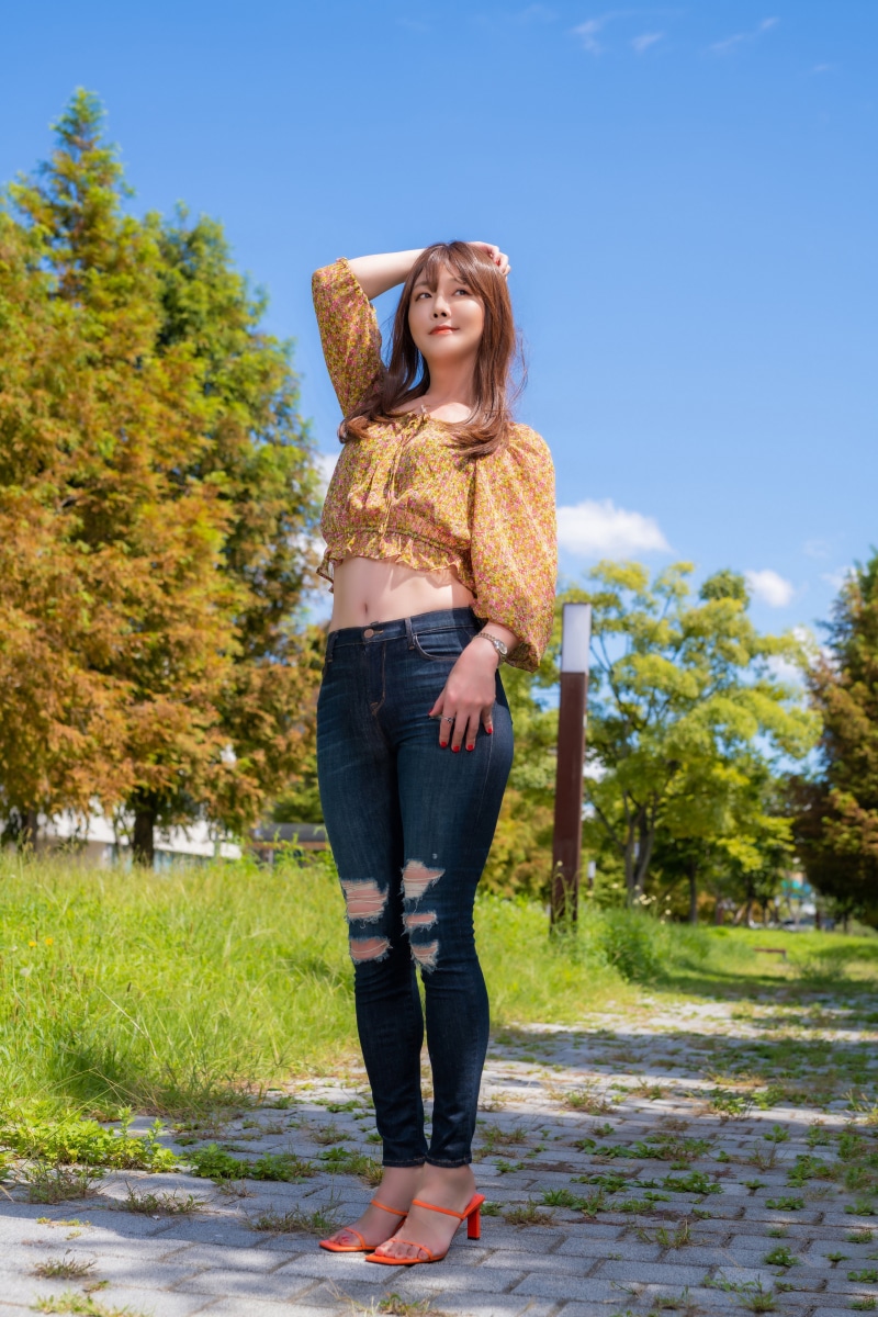 Asian woman in floral crop top and ripped jeans posing outdoors