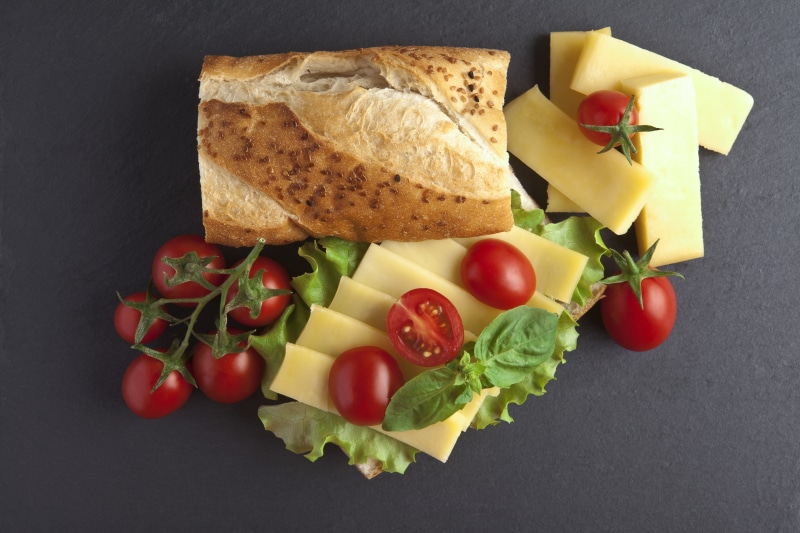 Sandwich with cheese, tomatoes, and lettuce on a dark background