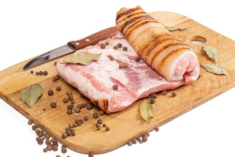 Pork belly with peppercorns and bay leaves on a cutting board