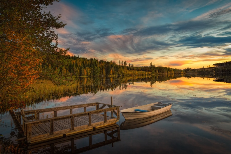 Wooden dock and boat on a lake at sunset