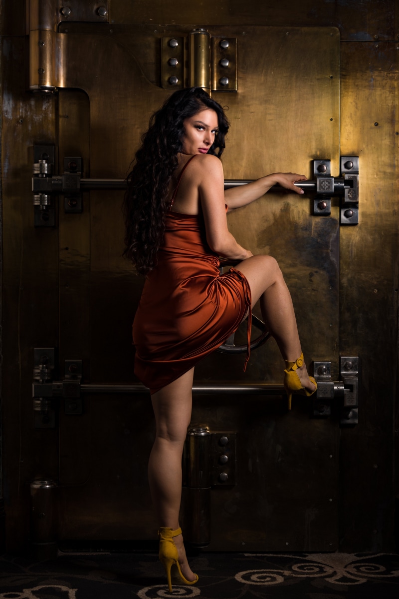 Woman in orange dress posing by a safe