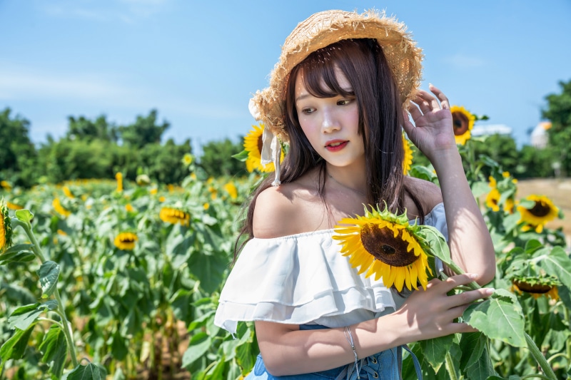 Asian girl in hat in sunflower field