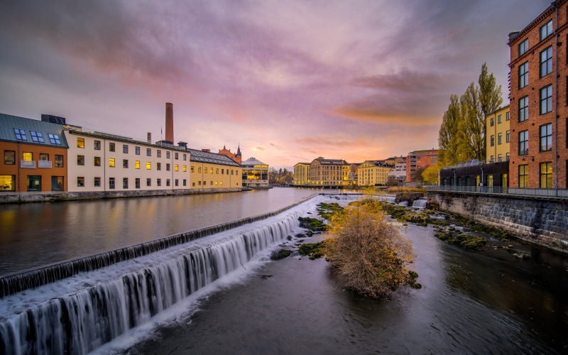 River with waterfall and buildings at sunset, Sweden